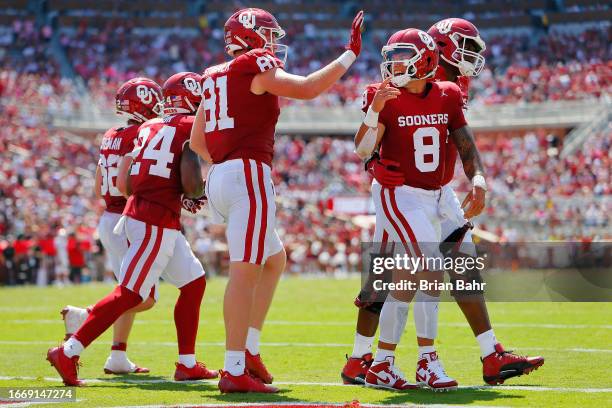 Quarterback Dillon Gabriel of the Oklahoma Sooners celebrates his five-yard touchdown run with tight end Austin Stogner and left tackle Cayden Green...