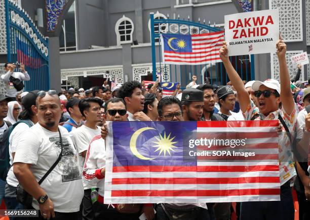 Protesters hold a placard and Malaysians flags during the Save Malaysia rally. Protesters rally against the controversial decision to halt the...