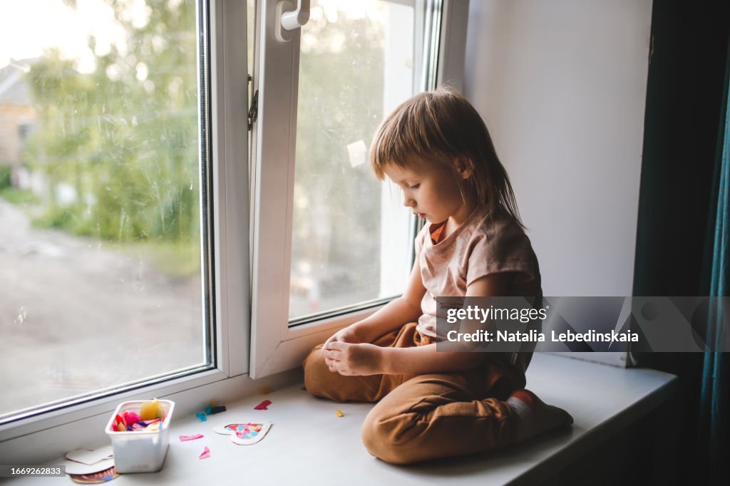 Sensory Playtime: Child's DIY Window Decorations alone sitting on windowsill