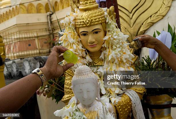 People pour water on a Buddha statue at the Shwedagon Pagoda. Every year in July, hundreds of thousands of people gather at the sacred Shwedagon...