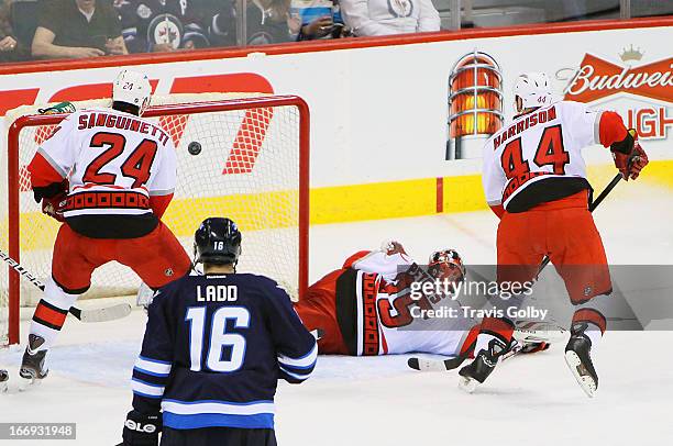 Andrew Ladd of the Winnipeg Jets, Bobby Sanguinetti and Jay Harrison of the Carolina Hurricanes watch as the puck flies in past goaltender Justin...