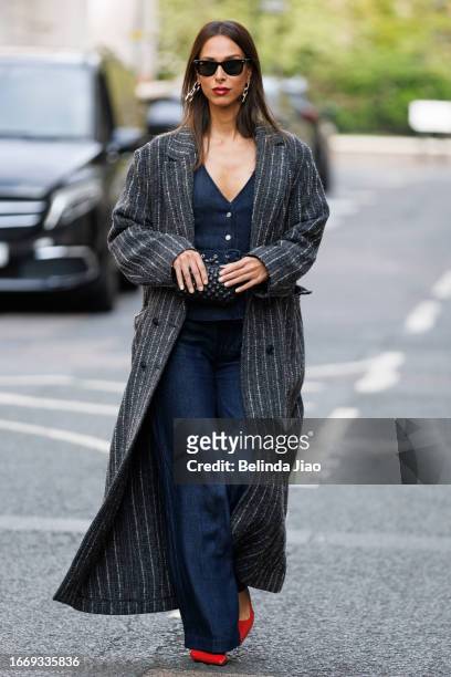 Isabella Charlotta Poppius seen wearing black Ray Ban sunglasses, a denim bodysuit from 7 For All Mankind beneath a vintage reworked Celine coat, red...