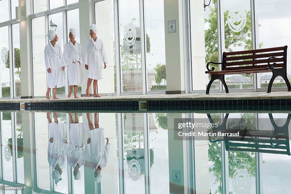 Women in bathrobes walking along swimming pool at spa