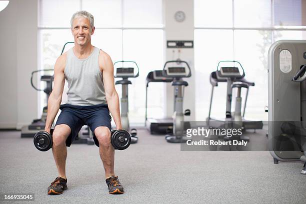 retrato de hombre sonriente haciendo squats con pesas en el gimnasio - hombre agachado fotografías e imágenes de stock