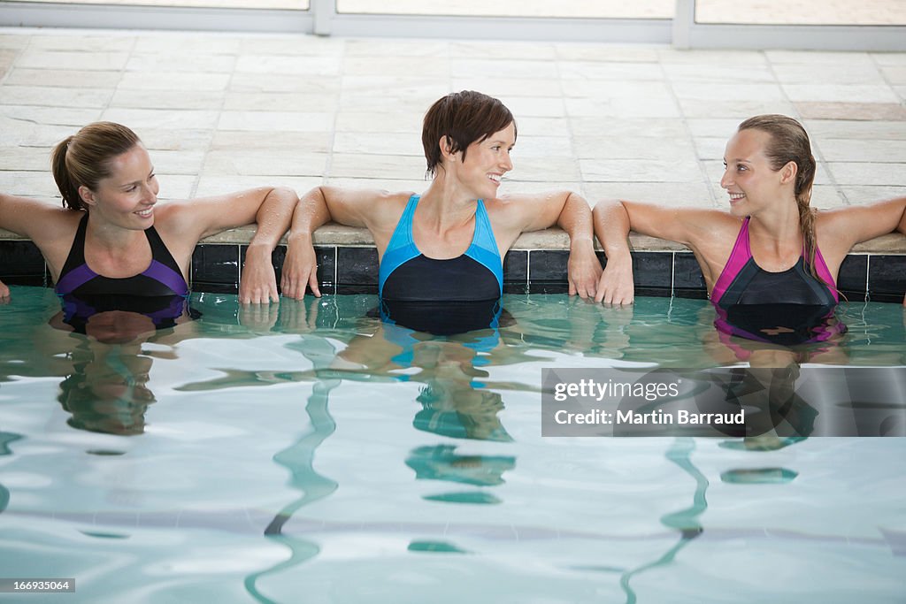 Portrait of smiling women leaning on edge of swimming pool