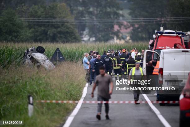 Rescuers stand near the remains of a car hit by a plane of the Frecce Tricolori national aerobatic team which fell after an accident during take off...