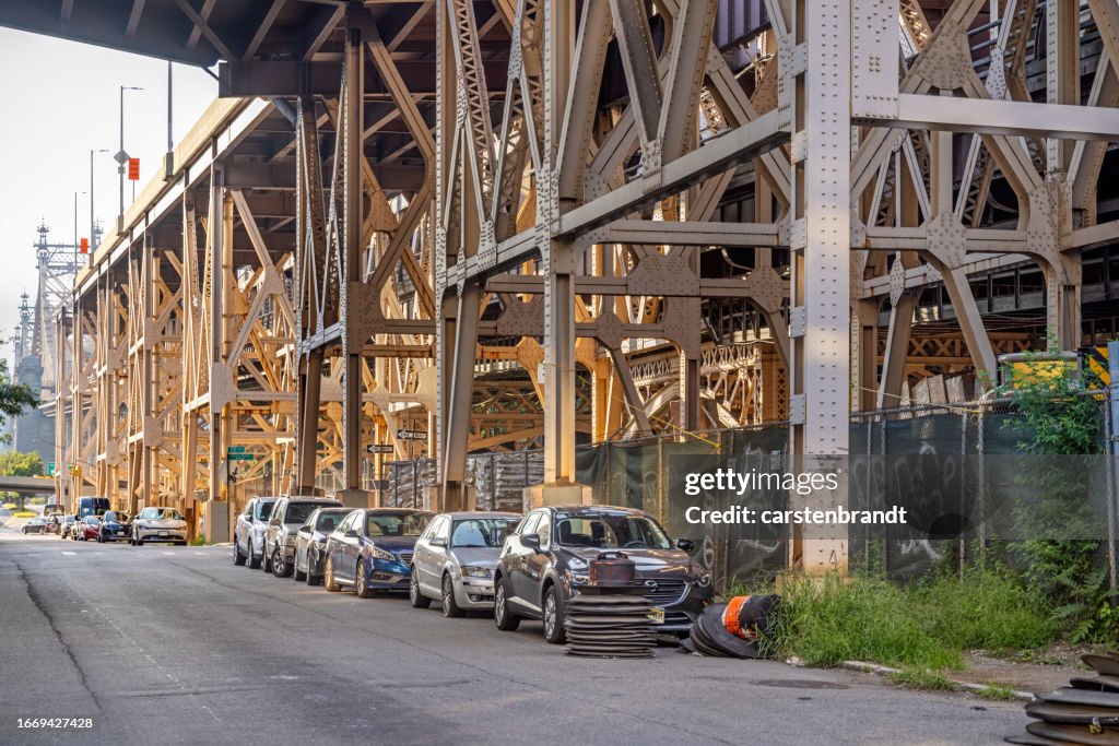 Parked cars under a large steel bridge