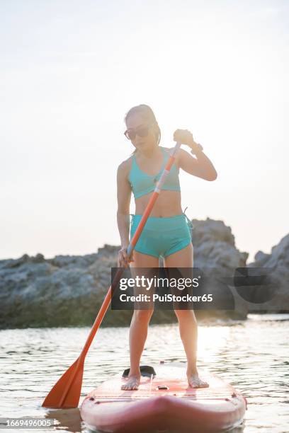 asian athletic woman on paddle board at the sea. solo outdoor water sport and travel on summer holiday thailand. - similan islands stock pictures, royalty-free photos & images