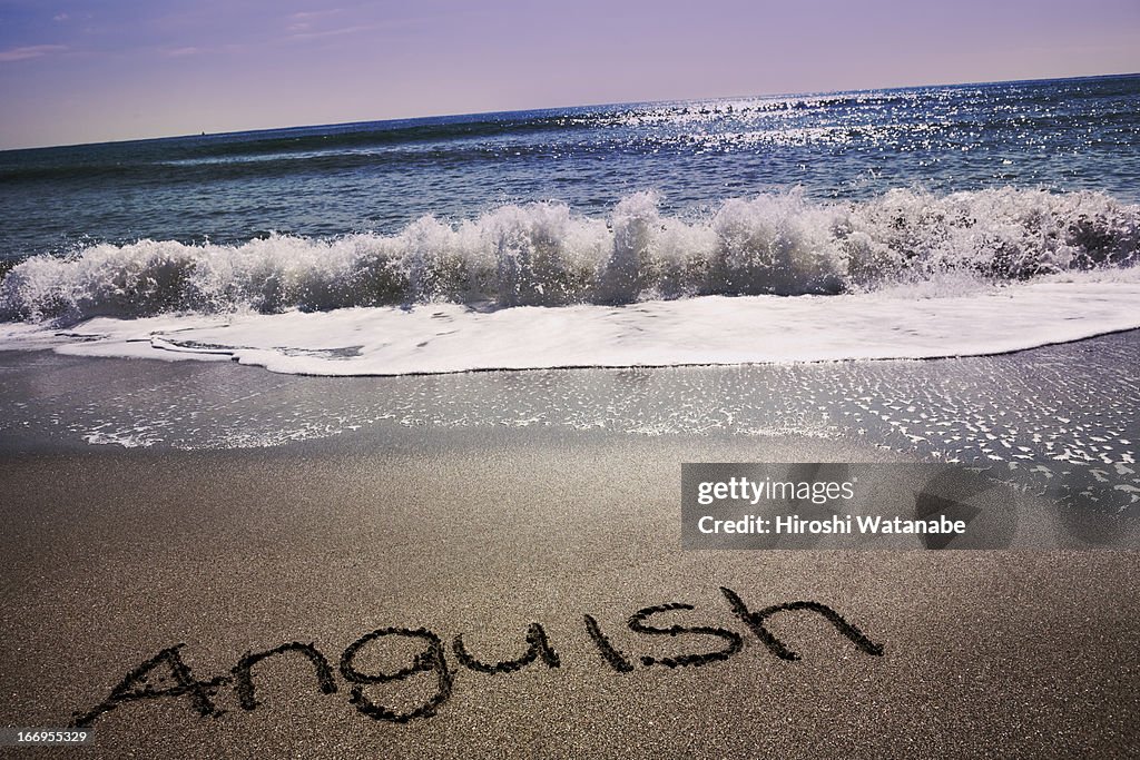 "Anguish" written in sand on beach