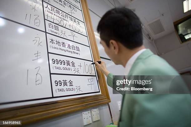 An employee of The Chinese Gold and Silver Exchange Society writes down prices of gold on the board in the trading hall of The Chinese Gold and...