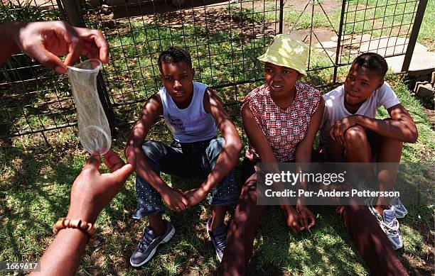 An unidentified female Aids educator shows three unidentified women how to use a female condom during an Aids awareness campaign on November 30, 2002...