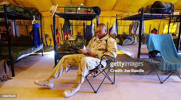 Marine Gunnery Sgt. Jab Smith from Leeland, Mississippi, finds a moment to read December 3, 2002 at Camp Commando in Kuwait. He is part of the...