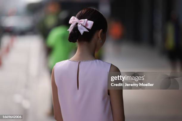 Christinna Kuan is seen wearing silver earrings, a rose bow with rhinestones details in her hair, a rose matching two-piece consisting of a mini...