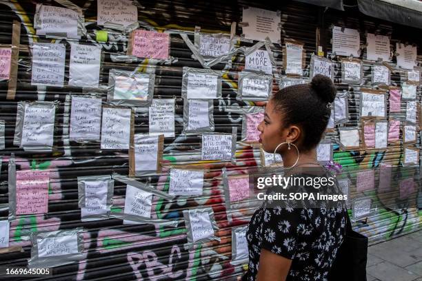 Woman reads signs and messages at Peckham Hair and Cosmetics on Rye Lane relating to a video circulating on social media. The video shows a scuffle...