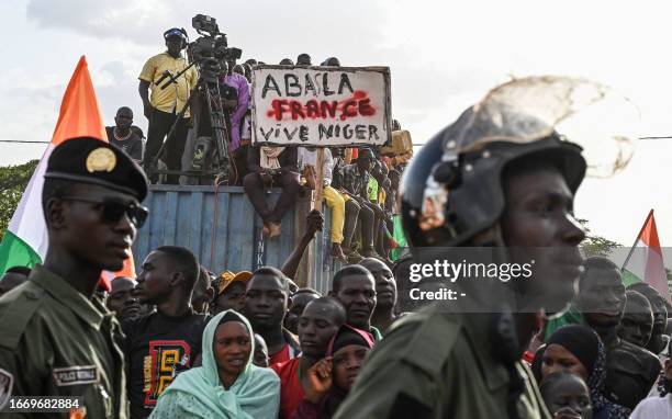 Supporters of Niger's National Council of Safeguard of the Homeland holds a placard as people protest ouside the Niger and French airbase to demand...