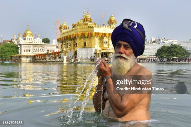 Devotee takes a dip in the holy sarovar at the Golden Temple on occasion of the 419th anniversary of the Installation of the 'Guru Granth Sahib' the...