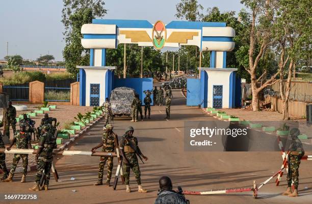 Soldiers stand guard as supporters of Niger's National Council of Safeguard of the Homeland protest ouside the Niger and French airbase to demand the...