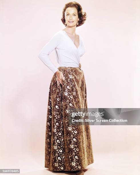 American actress Dina Merrill wearing a white top and ankle-length, floral-patterned skirt, circa 1955.