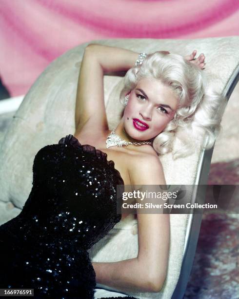 American actress Jayne Mansfield reclining on a chaise longue in a strapless, sequined gown and diamond jewelry, circa 1955.