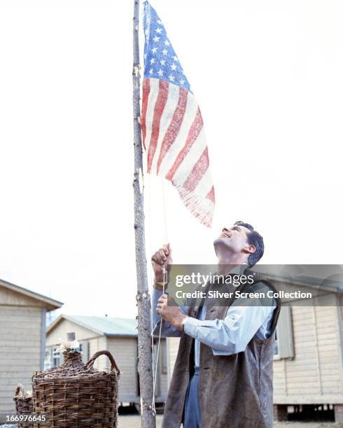 Lieutenant Bob Hendley raises the US flag in a scene from 'The Great Escape', directed by John Sturges, 1963.