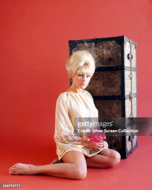 German actress Elke Sommer sitting by a packing trunk, circa 1965.