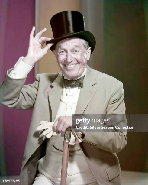 French cabaret singer and actor Maurice Chevalier posing with a top hat and cane in a promotional portrait for director Vincente Minnelli's film,...