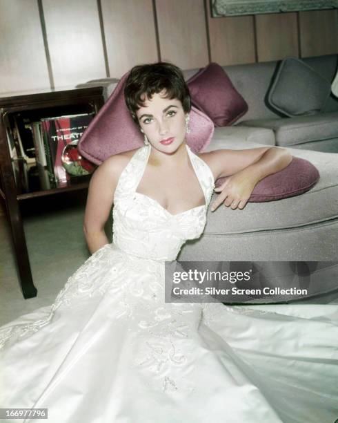 British-born American actress Elizabeth Taylor in a full length, white satin dress, 1954.
