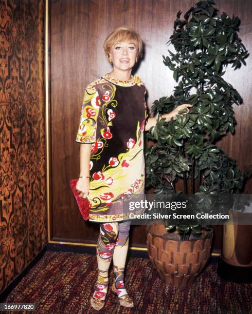 Welsh actress Glynis Johns wearing a dress in an Art Nouveau print, with matching tights, circa 1965.