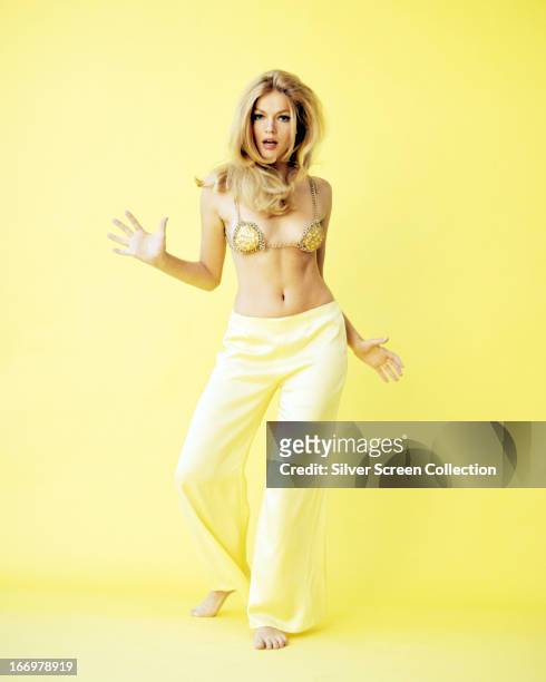 American actress Karen Jensen dancing in a yellow bra top and yellow trousers, circa 1970.
