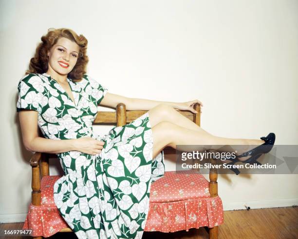 American actress Rita Hayworth reclining in a green and white, leaf-patterned dress, circa 1945.