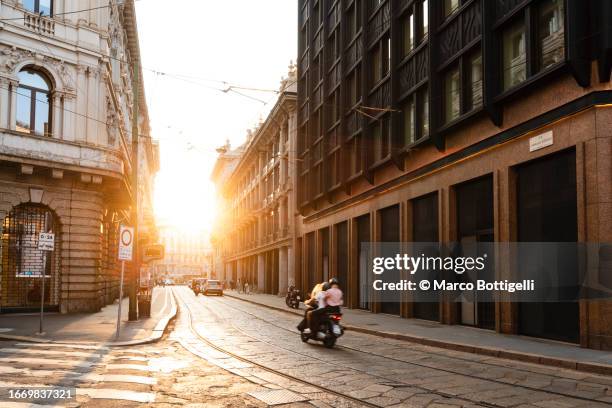 scooter driving at sunset in the streets of milan, italy - milan landmark stock pictures, royalty-free photos & images