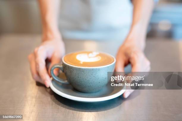 customer relationships and increase sales with personalized marketing for the food and beverage industry. the unrecognizable waitress serving a cup of hot cappuccino coffee to a customer at a cafe counter. - personalized stock pictures, royalty-free photos & images