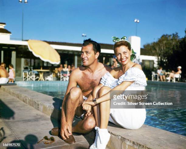 American actress and dancer Cyd Charisse sitting by a swimming pool with her husband, dancer Nico Charisse, circa 1945.
