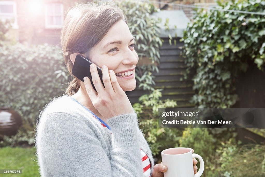 Woman talking on mobilephone in garden.