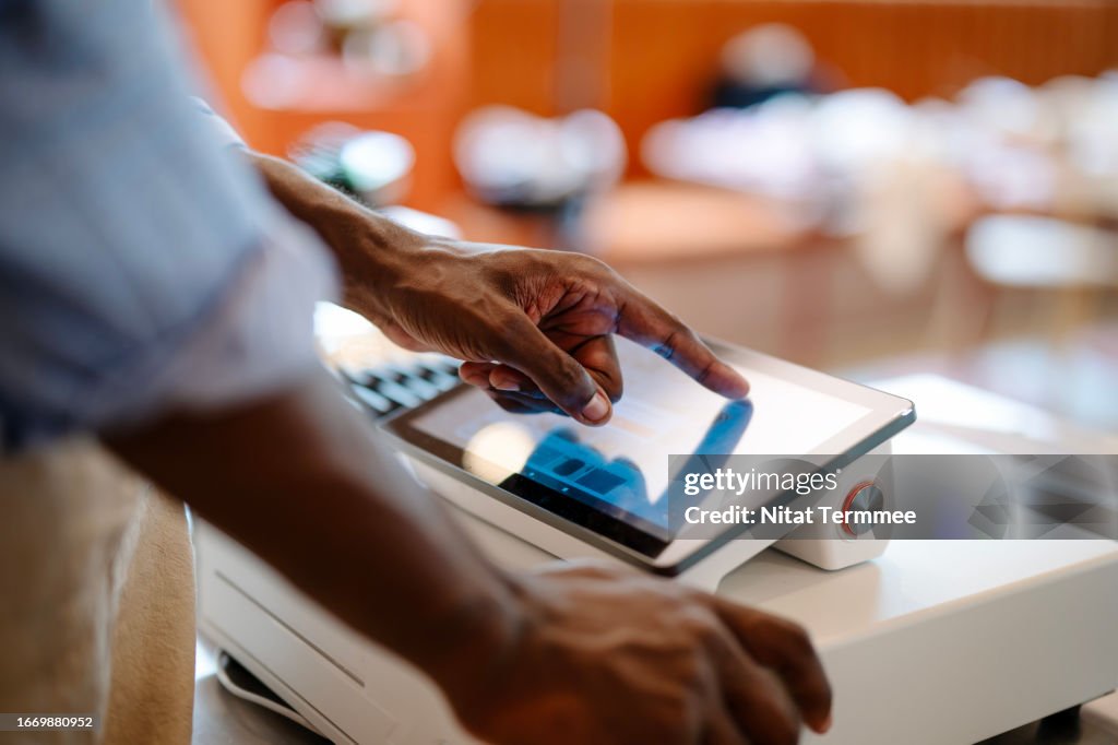 Contactless Ordering to Increase Ordering Experience and Improved Customer Retention and Transactions in Restaurant Business. Close-up shot of a male African-American cashier making orders from customers via the POS System at a cashier counter.