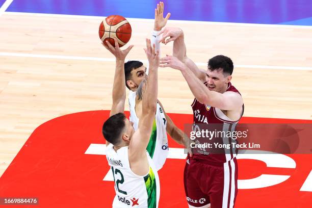 Rodions Kurucs of Latvia passes the ball against Gabrielius Maldunas and Deividas Sirvydis of Lithuania in the first quarter during the FIBA...