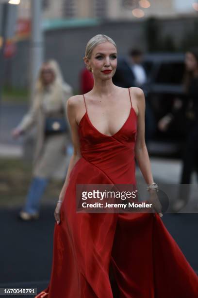 Leonie Hanne is seen outside Ralph Lauren show wearing gold Tiffany earrings, red flowing silk Ralph Lauren dress with open front, black leather...