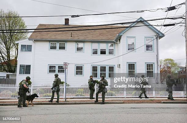 Team members stand in front of a house while looking for 19-year-old bombing suspect Dzhokhar A. Tsarnaev, during a door-to-door search on April 19,...