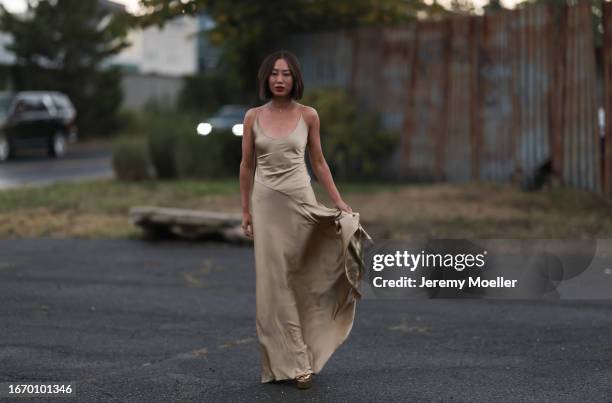 Aimee Song is seen outside Ralph Lauren show wearing a golden necklace with a diamond, golden, flowing, silk, long Ralph Lauren dress without sleeves...