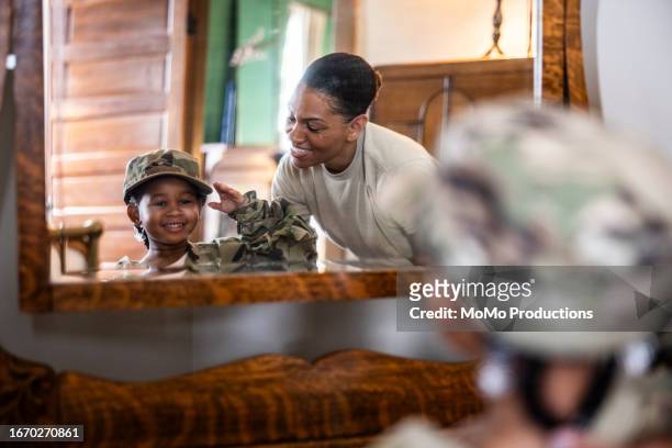daughter saluting female u.s. soldier mother in front mirror at home - child saluting stock pictures, royalty-free photos & images