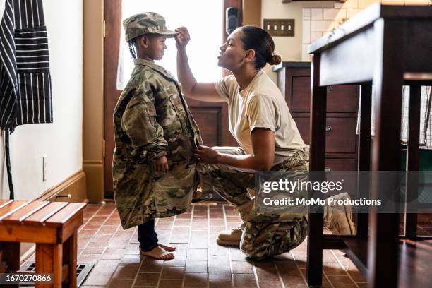 daughter wearing u.s. soldier mother's uniform at home - guerrero papel social fotografías e imágenes de stock