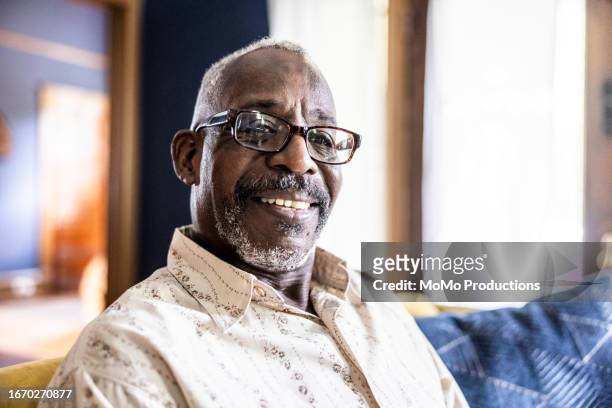portrait of senior man on couch at home - black population stock pictures, royalty-free photos & images