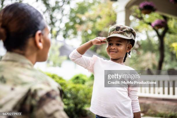 daughter saluting female u.s. soldier mother in front of home - kid power event in atlanta stock pictures, royalty-free photos & images