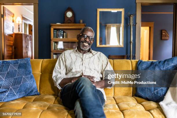 portrait of senior man on couch at home - couch stock pictures, royalty-free photos & images