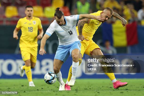 Sean Goldberg of Israel is challenged by Denis Alibec of Romania during the UEFA EURO 2024 European qualifier match between Romania and Israel at...