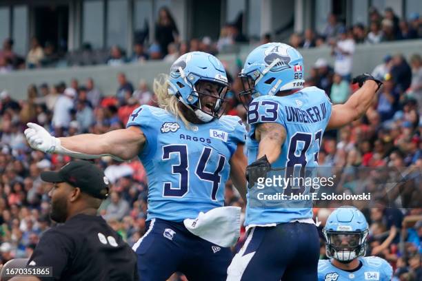 David Ungerer III congratulates AJ Ouellette of the Toronto Argonauts after his touchdown against the Montreal Alouettes during the second half at...