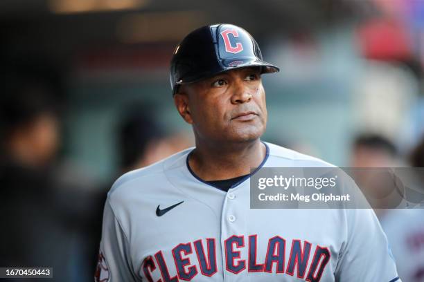 First base coach Sandy Alomar Jr. #15 of the Cleveland Guardians looks on from the dugout before the game against the Los Angeles Angels at Angel...