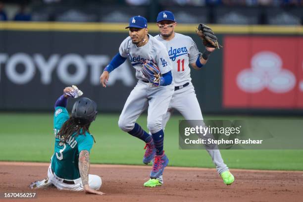 Second baseman Mookie Betts of the Los Angeles Dodgers hops out of the way after forcing out J.P. Crawford of the Seattle Mariners at second base...