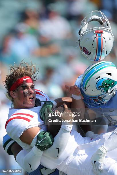 Jaxson Dart of the Mississippi Rebels is sacked by Jared Small of the Tulane Green Wave and Jesus Machado during the first half at Yulman Stadium on...