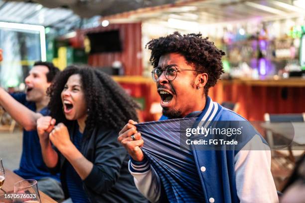 sports fans watching a match and celebrating at bar - football fan stock pictures, royalty-free photos & images